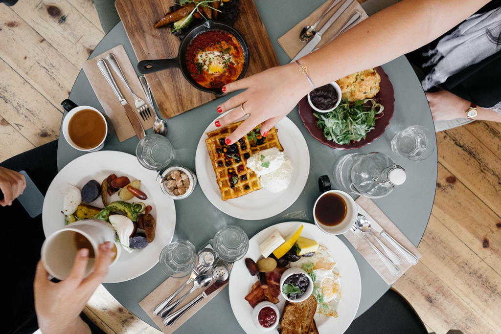 Overhead view of a group enjoying brunch with waffles and coffee on a cosy wooden table in Dublin.