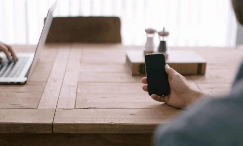 Man holding phone, laptop on desk, digital marketing agency, web design services, Dublin office setting.