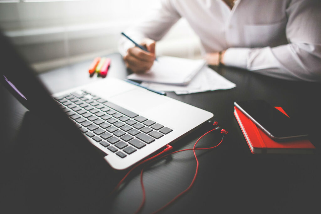 Modern workspace featuring a laptop and person writing, symbolising web design and digital marketing in Dublin.