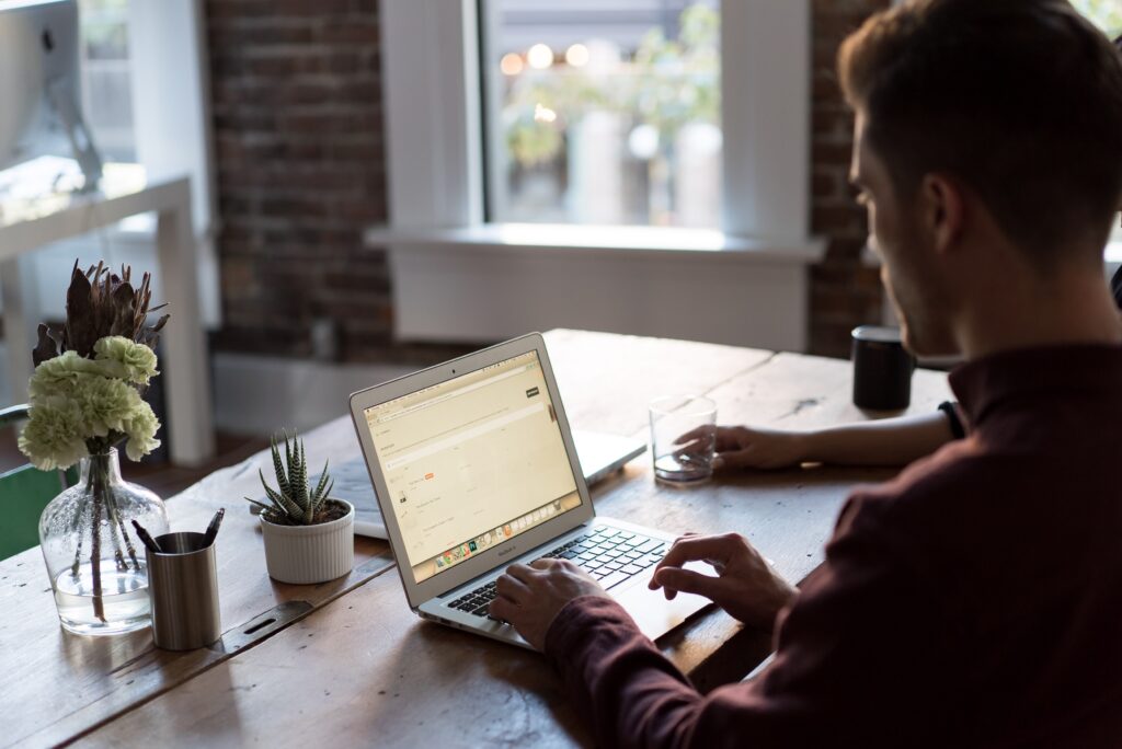 Man working on laptop, digital marketing agency office in Dublin, modern workspace with plants and natural light.