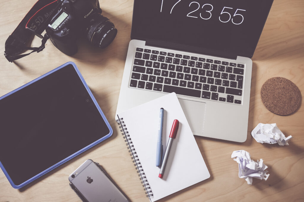 Workspace with laptop, tablet, camera, smartphone and notepad for web design and digital marketing in Dublin.