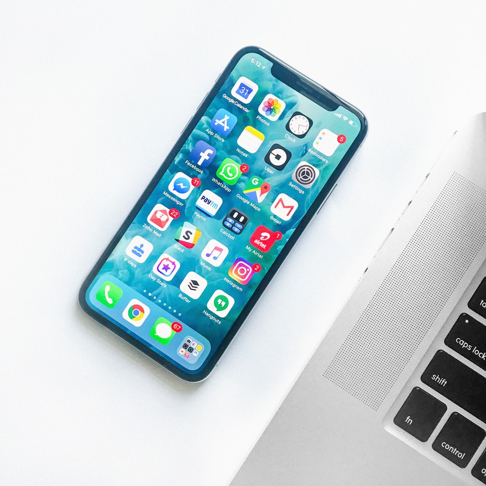 Smartphone with apps next to laptop on white desk; digital marketing tools showcase by Dublin agency.