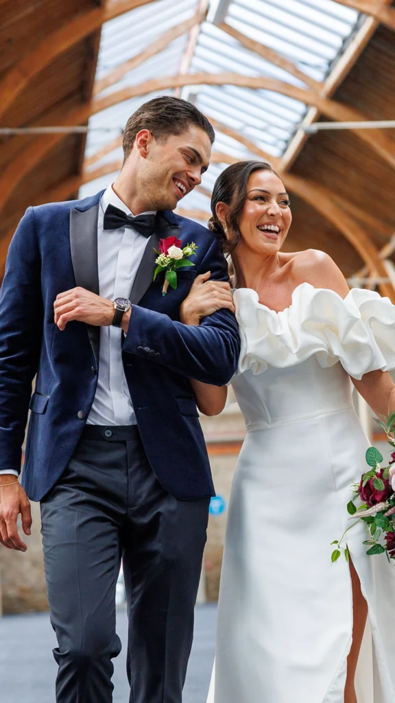 Happy couple walking arm in arm at a wedding in a venue with wooden ceilings in Dublin.